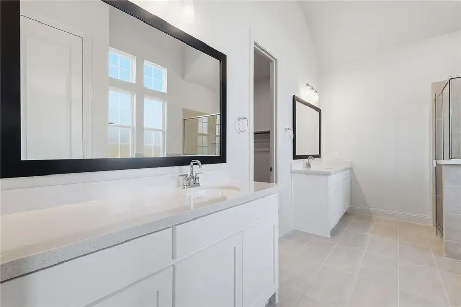 Full bathroom with two vanities, a shower stall, and light tile patterned floors