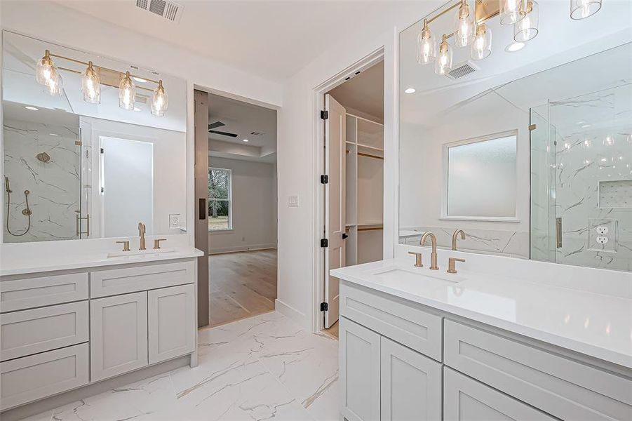 The room is bright and airy, featuring a sleek design with marble-like flooring and  quartz countertops, offering a luxurious feel.