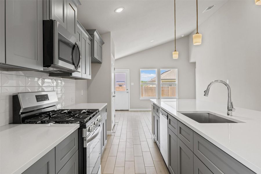 Vaulted ceilings and wood-look flooring enhance this modern kitchen with sleek solid-surface countertops. Vaulted ceilings and wood-look flooring enhance this modern kitchen with sleek solid-surface countertops.