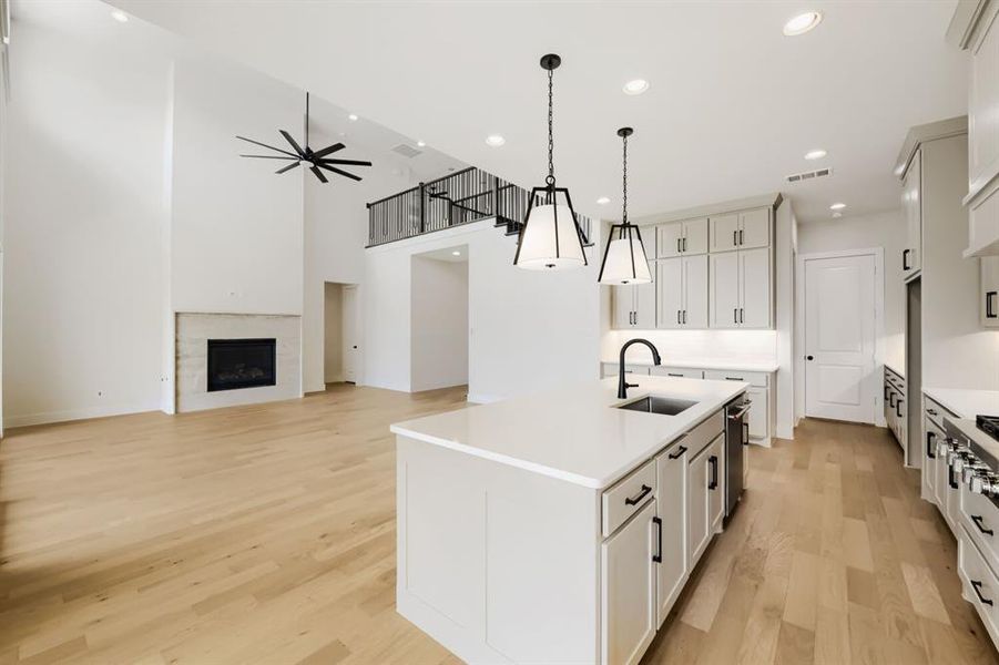Open-concept living area featuring a kitchen island with quartz countertops, a black single-basin sink, and pendant lighting Open-concept living area featuring a kitchen island with quartz countertops, a black single-basin sink, and pendant lighting