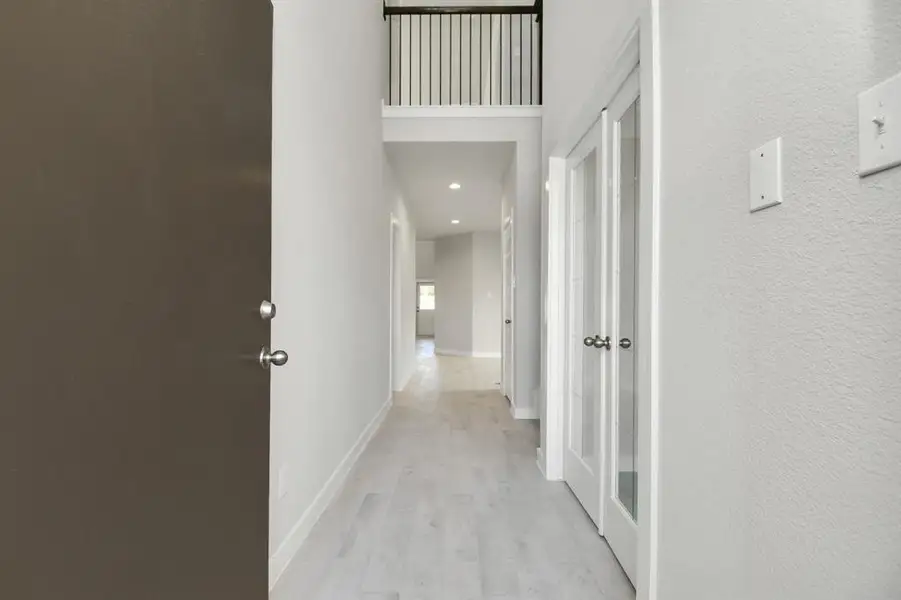 The grand entrance beckons with high ceilings, adorned with elegant wood-look tile flooring and oversized baseboards.