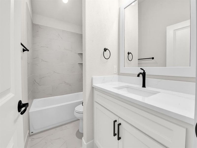 Bathroom featuring light marble finish flooring, vanity, and tub / shower combination