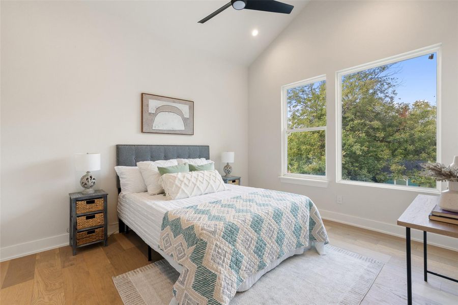 Bedroom with wood finished floors, high vaulted ceiling, a ceiling fan, and recessed lighting Bedroom with wood finished floors, high vaulted ceiling, a ceiling fan, and recessed lighting