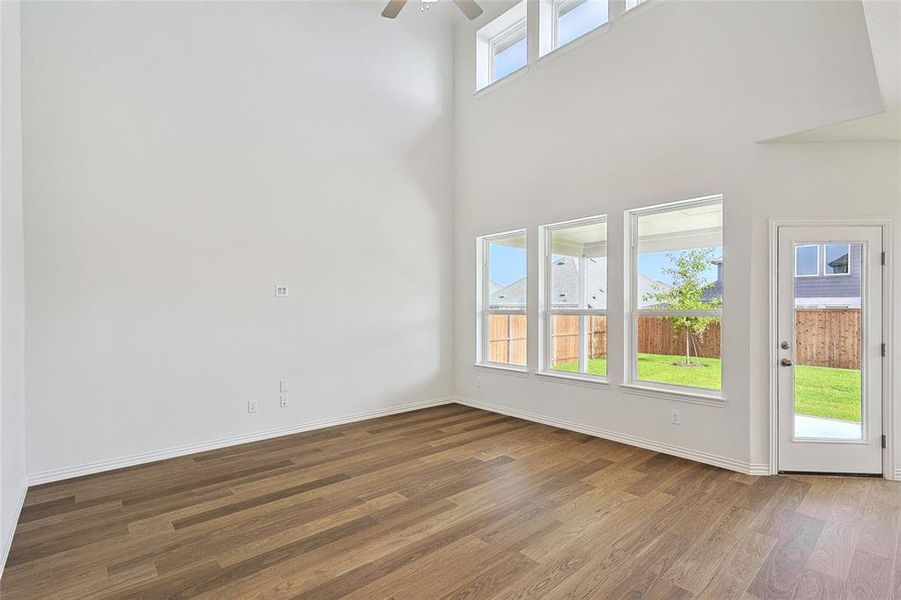 Spare room featuring wood-type flooring, a towering ceiling, and ceiling fan