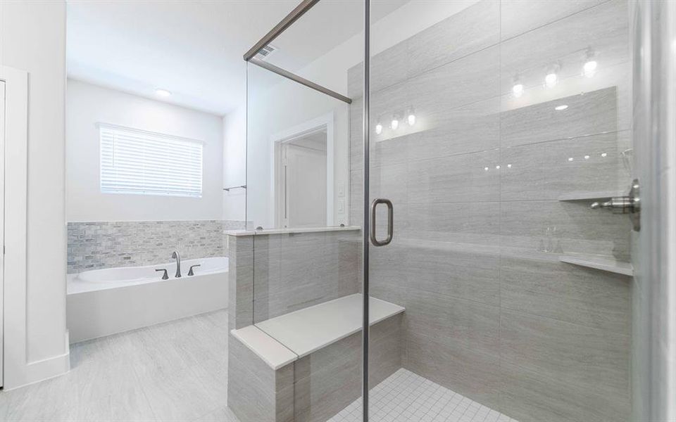 Spacious bathroom featuring a frameless glass shower enclosure with a built-in bench, a separate soaking tub with a mosaic tile surround, and light-toned tile flooring