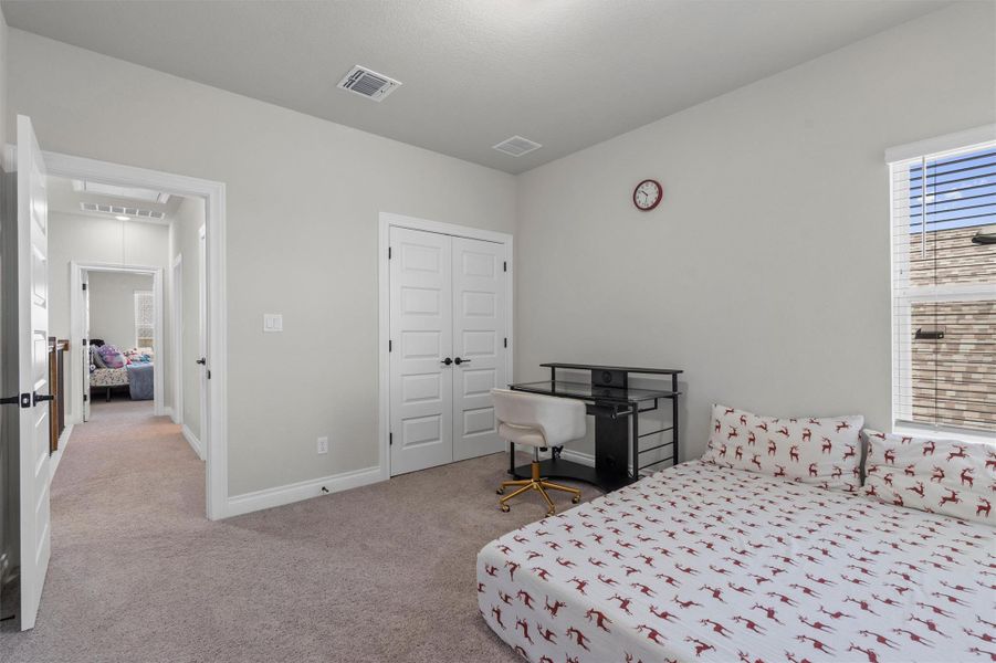 Plush carpeting anchors this bedroom with a large window and double closet doors.