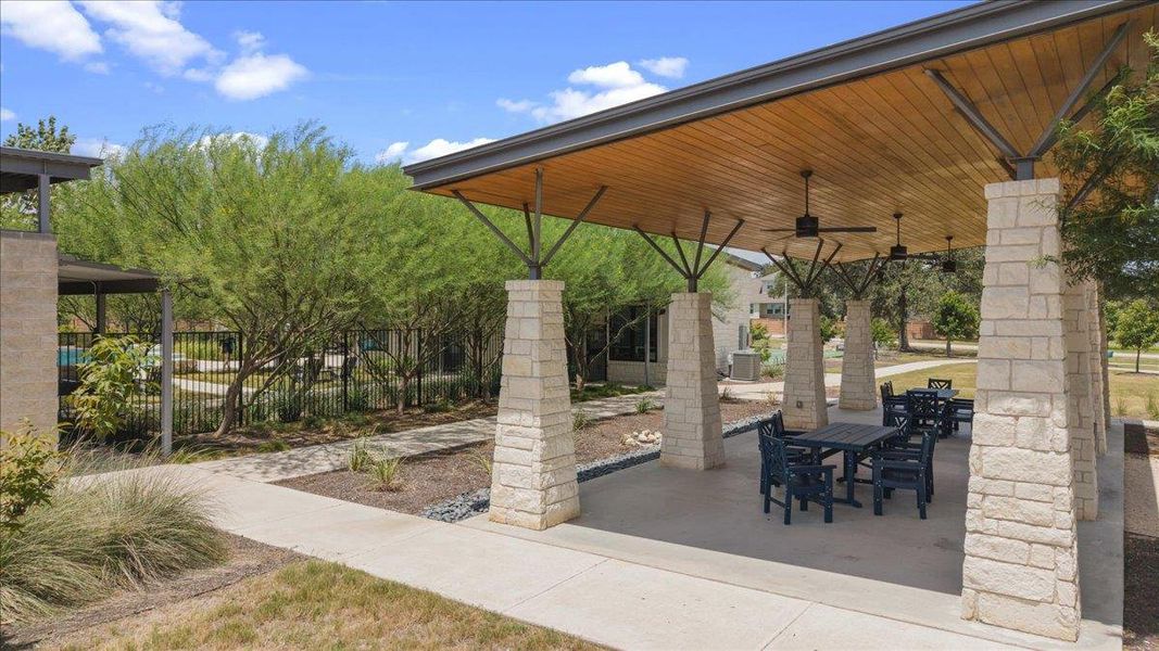 An inviting stone-pillared pavilion with a polished tongue-and-groove ceiling sits alongside manicured pathways.