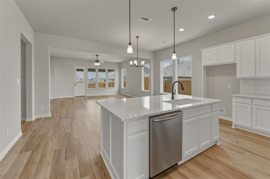 Kitchen island featuring a white countertop, undermount sink with a black gooseneck faucet, and a stainless steel dishwasher Kitchen island featuring a white countertop, undermount sink with a black gooseneck faucet, and a stainless steel dishwasher