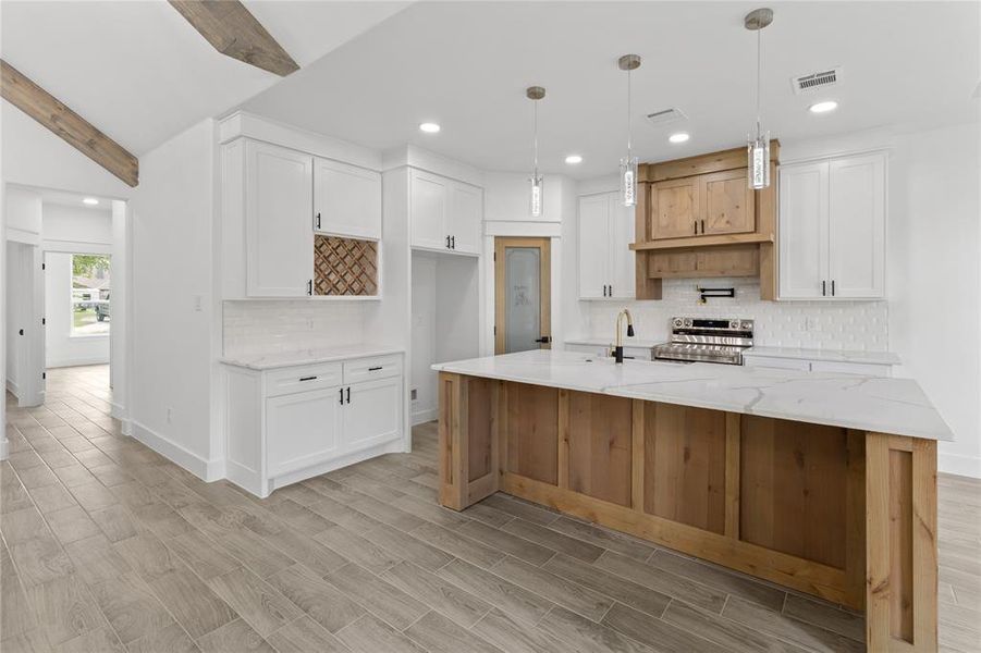 Kitchen featuring light stone countertops, decorative light fixtures, light hardwood / wood-style floors, white cabinetry, and stainless steel range with electric stovetop