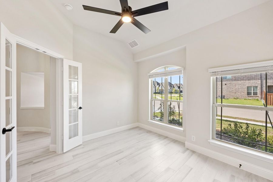 Empty room with light wood floors, ceiling fan, arched window, and French doors Empty room with light wood floors, ceiling fan, arched window, and French doors