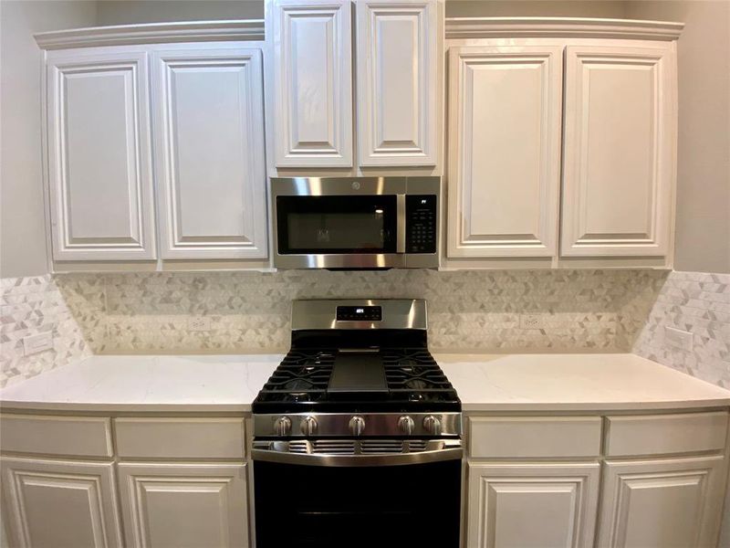 Kitchen has white raised panel cabinets, decorative light mosaic tile backsplash, Calacatta Lincoln white w/grey veined quartz counters, and stainess GE GAS appliances Kitchen has white raised panel cabinets, decorative light mosaic tile backsplash, Calacatta Lincoln white w/grey veined quartz counters, and stainess GE GAS appliances