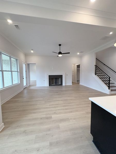 Expansive living area featuring light wood-finish flooring, a contemporary fireplace with a white mantel, and recessed lighting Expansive living area featuring light wood-finish flooring, a contemporary fireplace with a white mantel, and recessed lighting