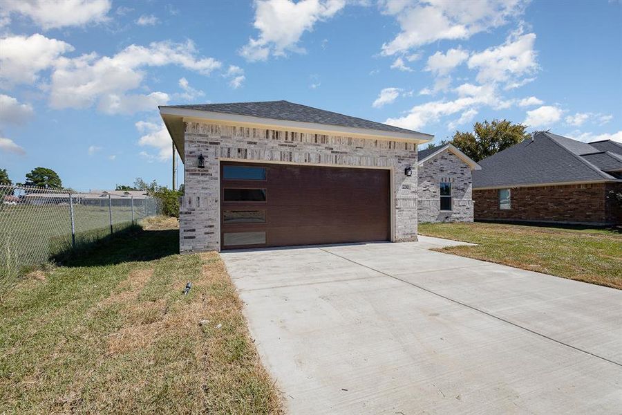 Garage featuring concrete driveway and fence