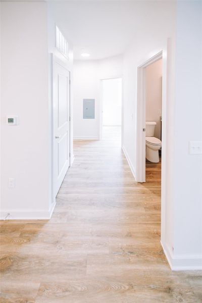 Hall featuring electric panel, light wood finished floors, and baseboards