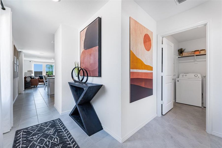 Corridor featuring light tile patterned flooring and washer and dryer