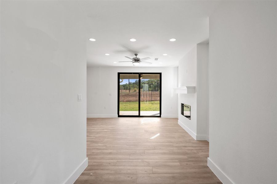 Unfurnished living room featuring recessed lighting, light wood-style flooring, a glass covered fireplace, and a ceiling fan