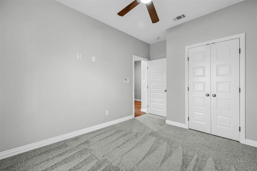 Unfurnished bedroom with carpet, ceiling fan, and a closet