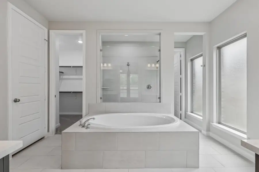 Bathroom with a stall shower, a garden tub, vanity, a spacious closet, and tile patterned floors Bathroom with a stall shower, a garden tub, vanity, a spacious closet, and tile patterned floors