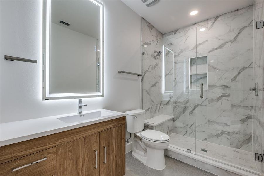 Bathroom featuring vanity, a marble finish shower, and recessed lighting