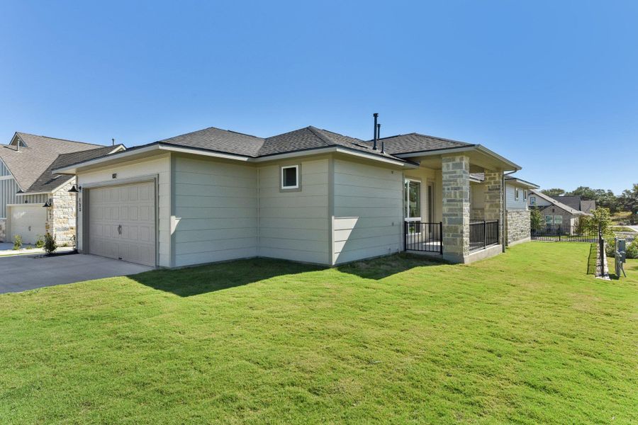 Back of property featuring a lawn, roof with shingles, and stone siding