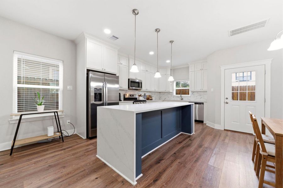 Contemporary finishes and designer lighting create a bright and inviting culinary space.