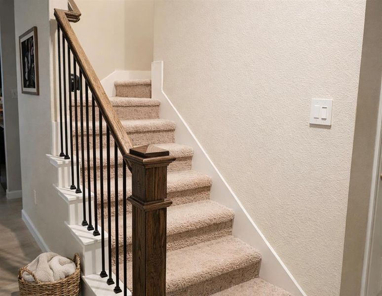 Stairway with a textured wall and baseboards
