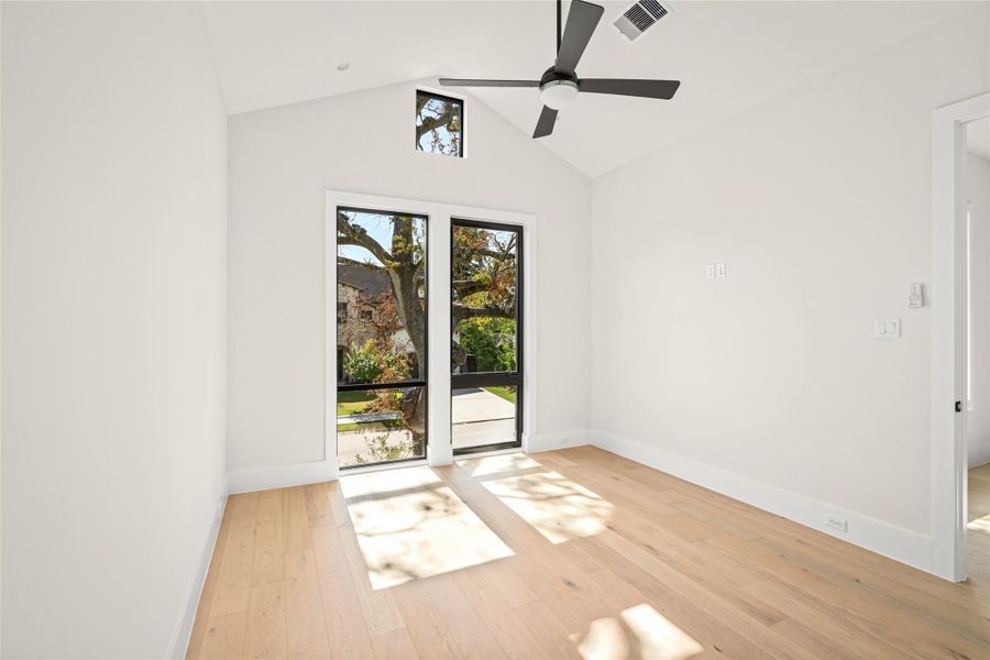 Versatile downstairs study with vaulted ceilings and modern black framed windows that fill the room with natural light. Perfect for a home office, guest suite, or additional bedroom with a serene front facing view. Versatile downstairs study with vaulted ceilings and modern black framed windows that fill the room with natural light. Perfect for a home office, guest suite, or additional bedroom with a serene front facing view.