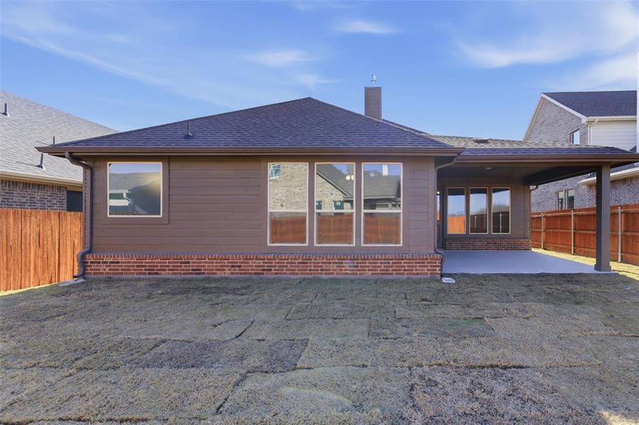 Rear view of house featuring a patio, a chimney, a shingled roof, and brick siding Rear view of house featuring a patio, a chimney, a shingled roof, and brick siding