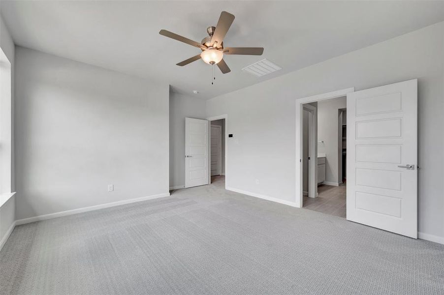 Spacious room featuring light gray carpeting, neutral wall finishes, and a contemporary ceiling fan with integrated lighting