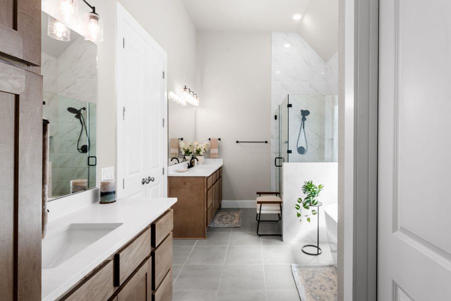Bathroom with dual wood-finish vanities featuring undermount sinks and light-toned countertops