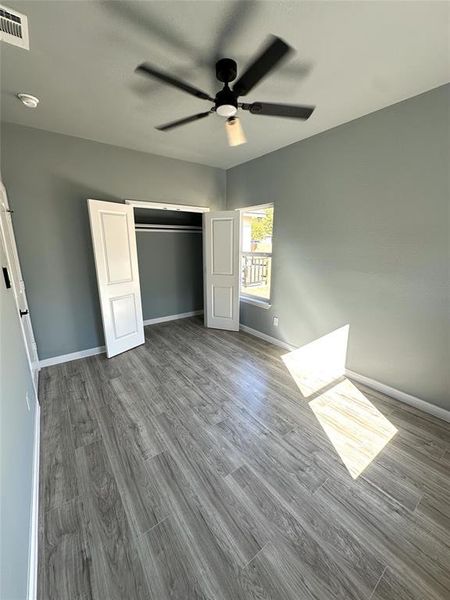 Unfurnished bedroom featuring hardwood / wood-style flooring, a closet, and ceiling fan