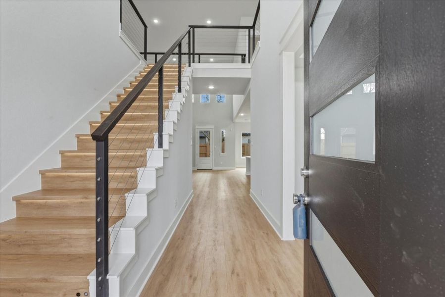 As you enter, the staircase to the left showcases luxury vinyl flooring, motion-sensor LED lighting on each step, and a sleek modern handrail.