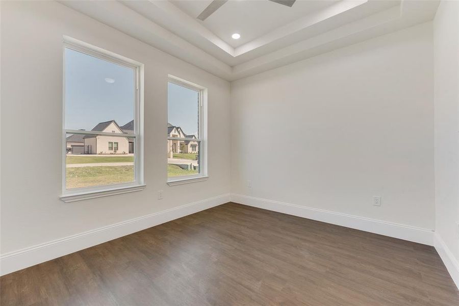 Expansive room featuring wood-finish flooring, white baseboards, and two large windows Expansive room featuring wood-finish flooring, white baseboards, and two large windows