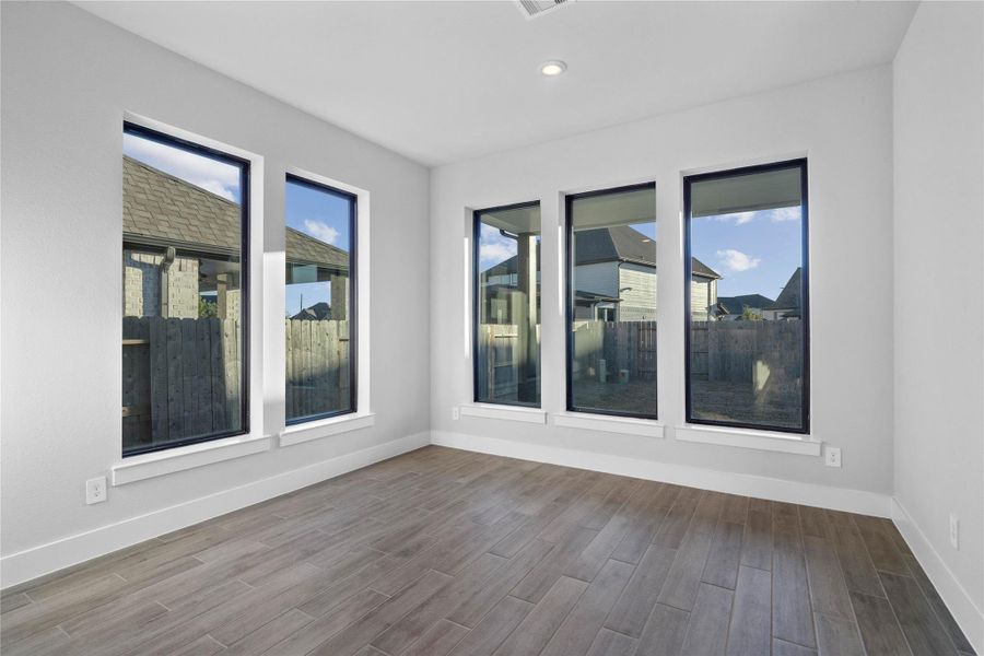 The breakfast room is filled with natural light and features high ceilings, recessed lighting, and expansive windows.