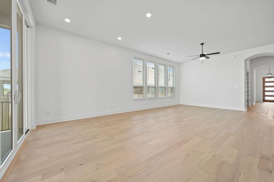 Empty room featuring arched walkways, light wood finished floors, recessed lighting, and ceiling fan