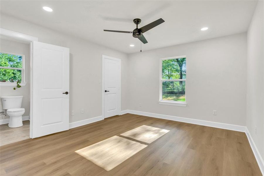 Unfurnished bedroom featuring light wood-type flooring, recessed lighting, connected bathroom, and ceiling fan Unfurnished bedroom featuring light wood-type flooring, recessed lighting, connected bathroom, and ceiling fan