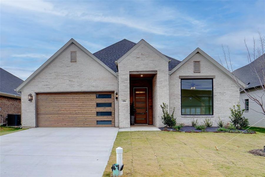 View of front of house with a front yard, a garage, and central air condition unit