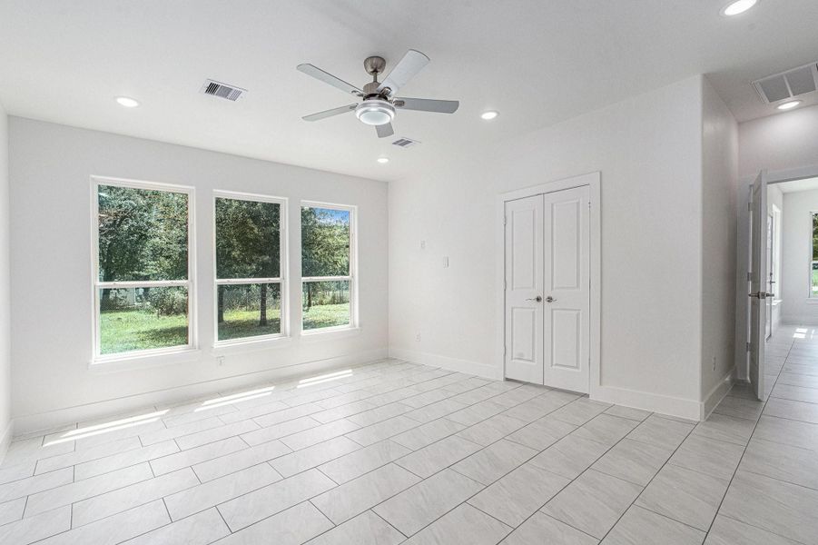 Bright, spacious room with large windows offering a view of greenery. Features modern tile flooring, a ceiling fan, and double doors, ideal for flexible use. Bright, spacious room with large windows offering a view of greenery. Features modern tile flooring, a ceiling fan, and double doors, ideal for flexible use.
