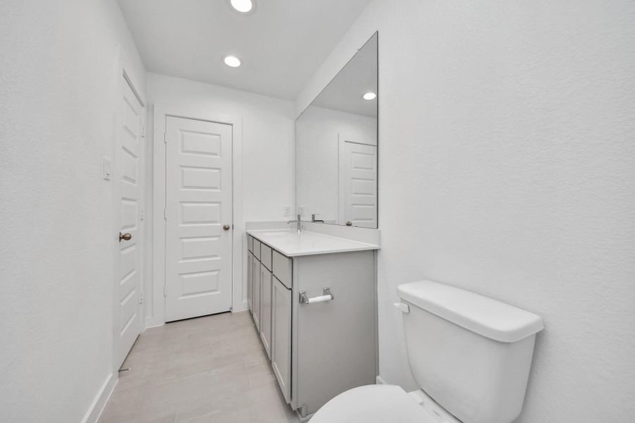Secondary bath features tile flooring, bath/shower combo with tile surround, light stained wood cabinets, beautiful light countertop. Sample photo of completed home with similar floor plan. Actual colors and selections may vary.