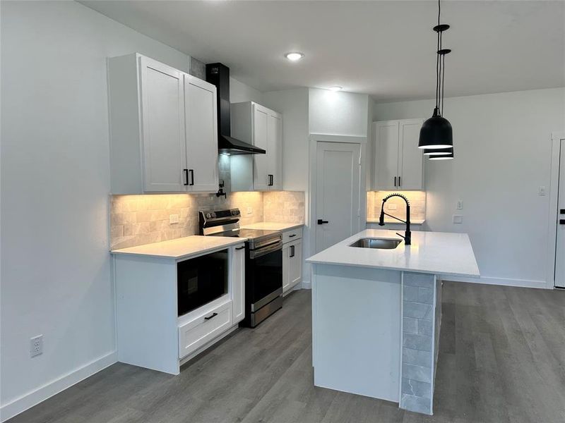 Kitchen featuring hanging light fixtures, white cabinetry, and stainless steel range with electric stovetop