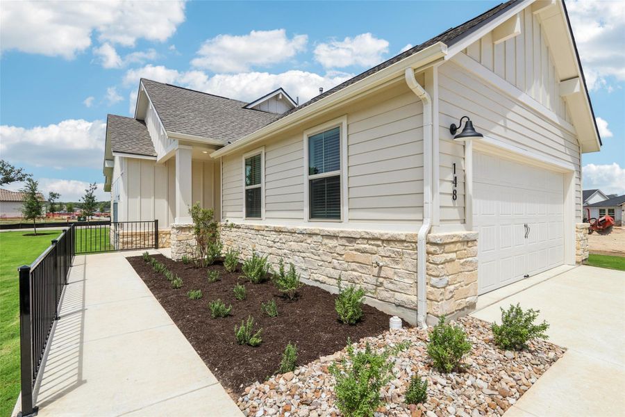 View of side of property featuring board and batten siding, a garage, a shingled roof, and stone siding