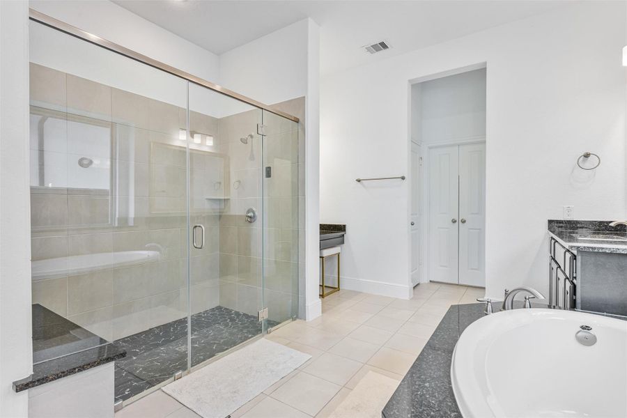 Primary bath boasts separate vanity sinks a nice sized garden tub, a make up vanity, large standing shower with bench, and wonderful natural light.