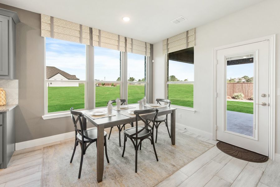 Dining area with four-chair table, large windows overlooking backyard, and glass back door