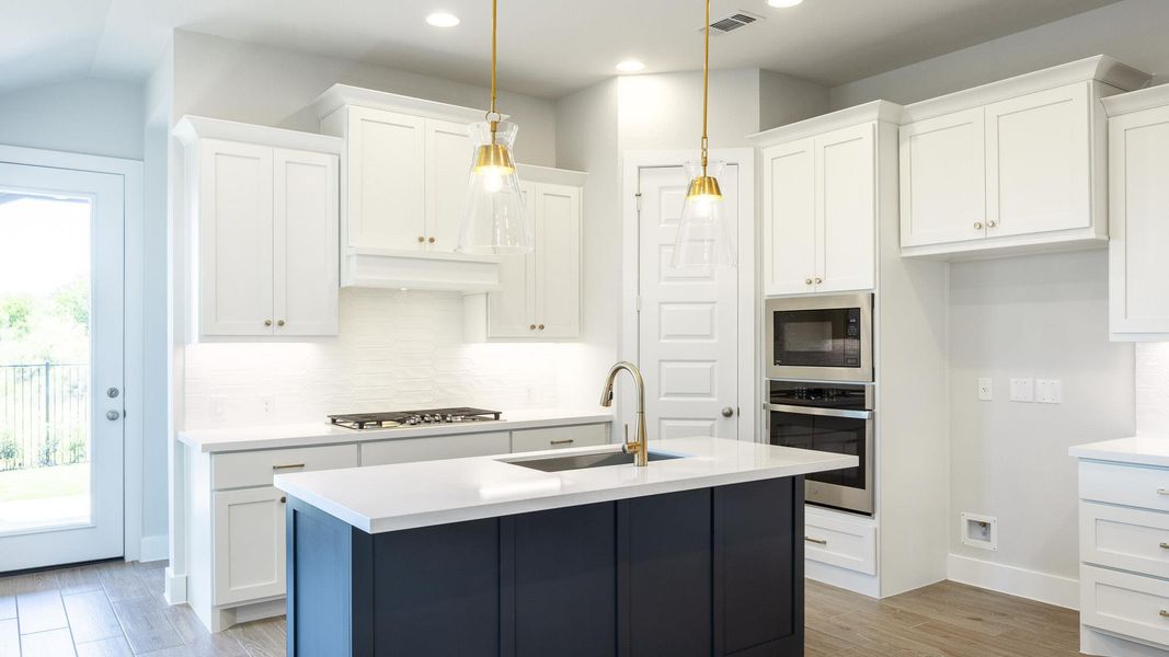 Kitchen featuring white cabinets, stainless steel appliances, light wood-type flooring, an island with sink, and tasteful backsplash
