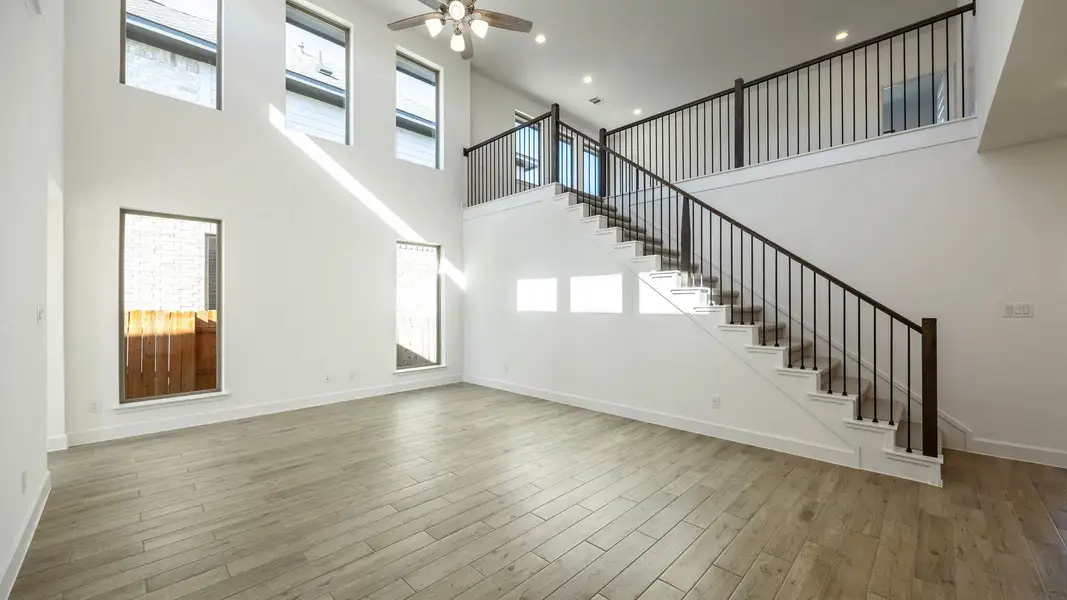 Unfurnished living room with plenty of natural light, a high ceiling, light wood-style floors, ceiling fan, and recessed lighting
