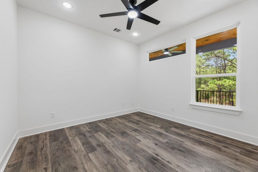 Hardwood floors and a sleek ceiling fan define this spacious room, with ample natural light.
