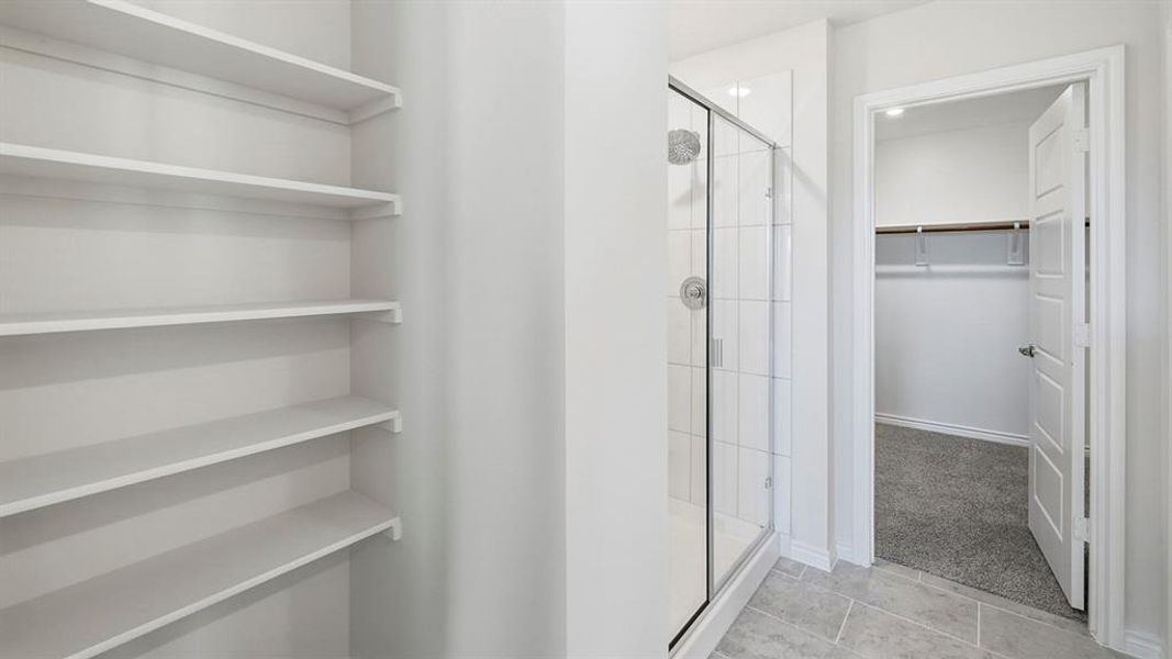 Bathroom featuring a walk in closet, a shower stall, and light tile patterned floors Bathroom featuring a walk in closet, a shower stall, and light tile patterned floors