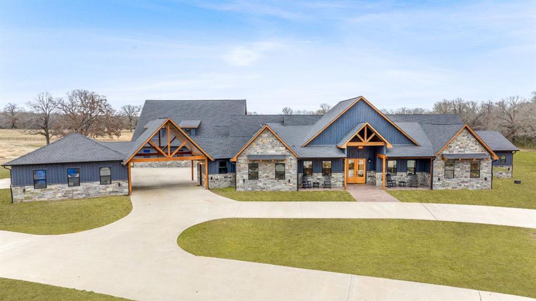 View of front of house with stone siding and a front lawn