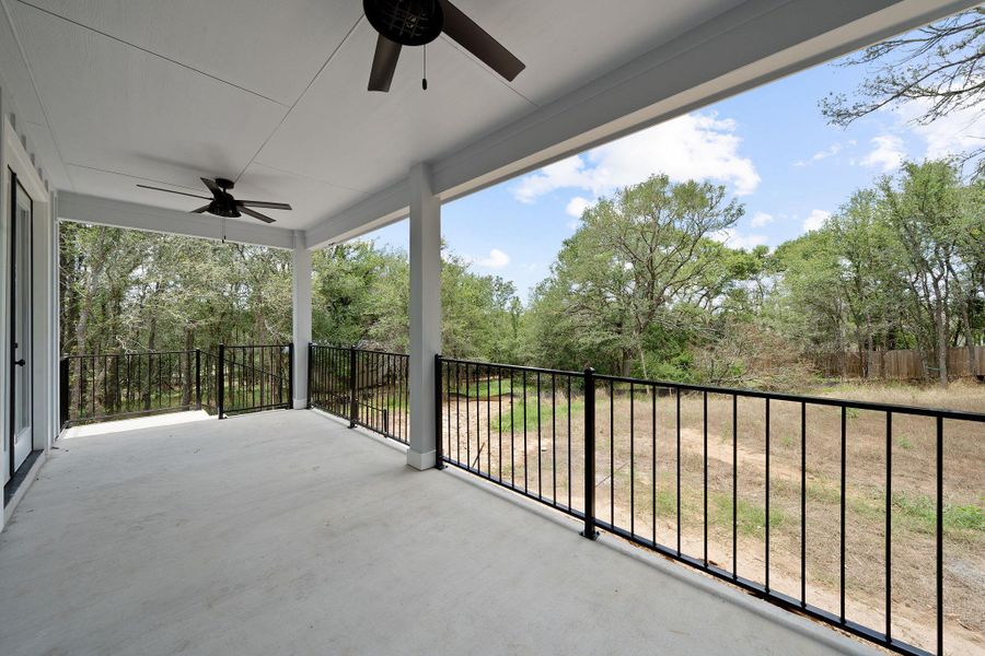 Covered outdoor patio with concrete flooring, black metal railings, and two ceiling fans