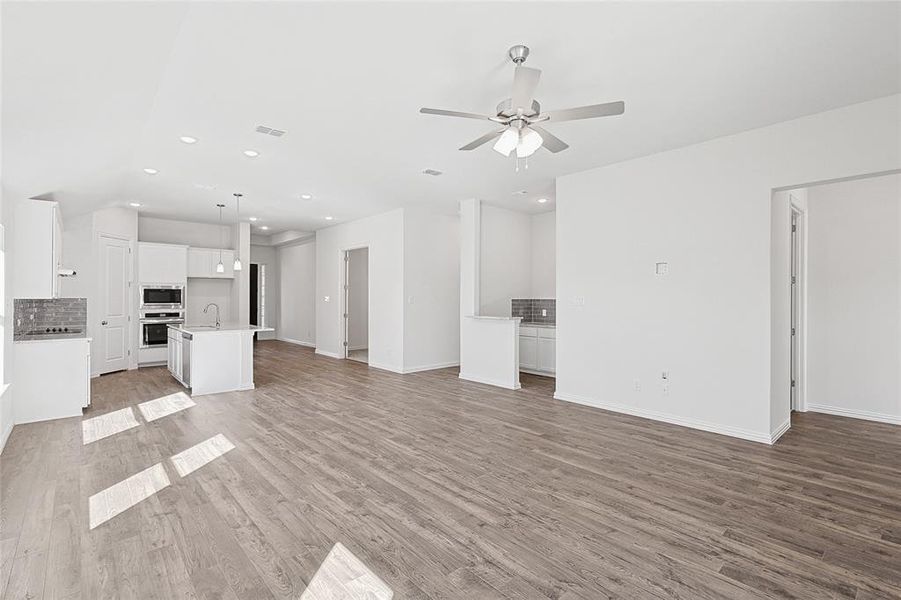 Unfurnished living room with hardwood / wood-style flooring, ceiling fan, and sink